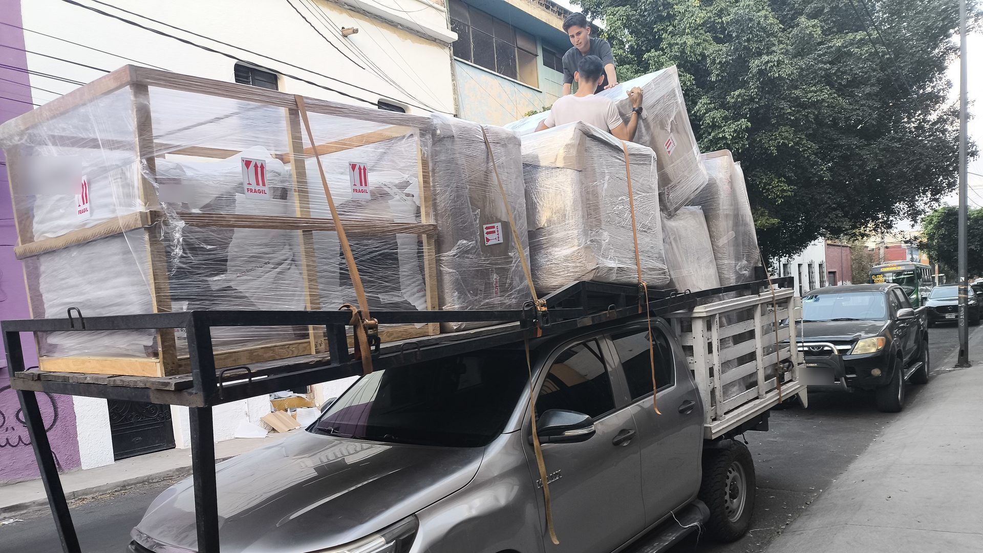 Hilux de Flete Express cargada con muebles emplayados y dos personas del equipo acomodando la carga