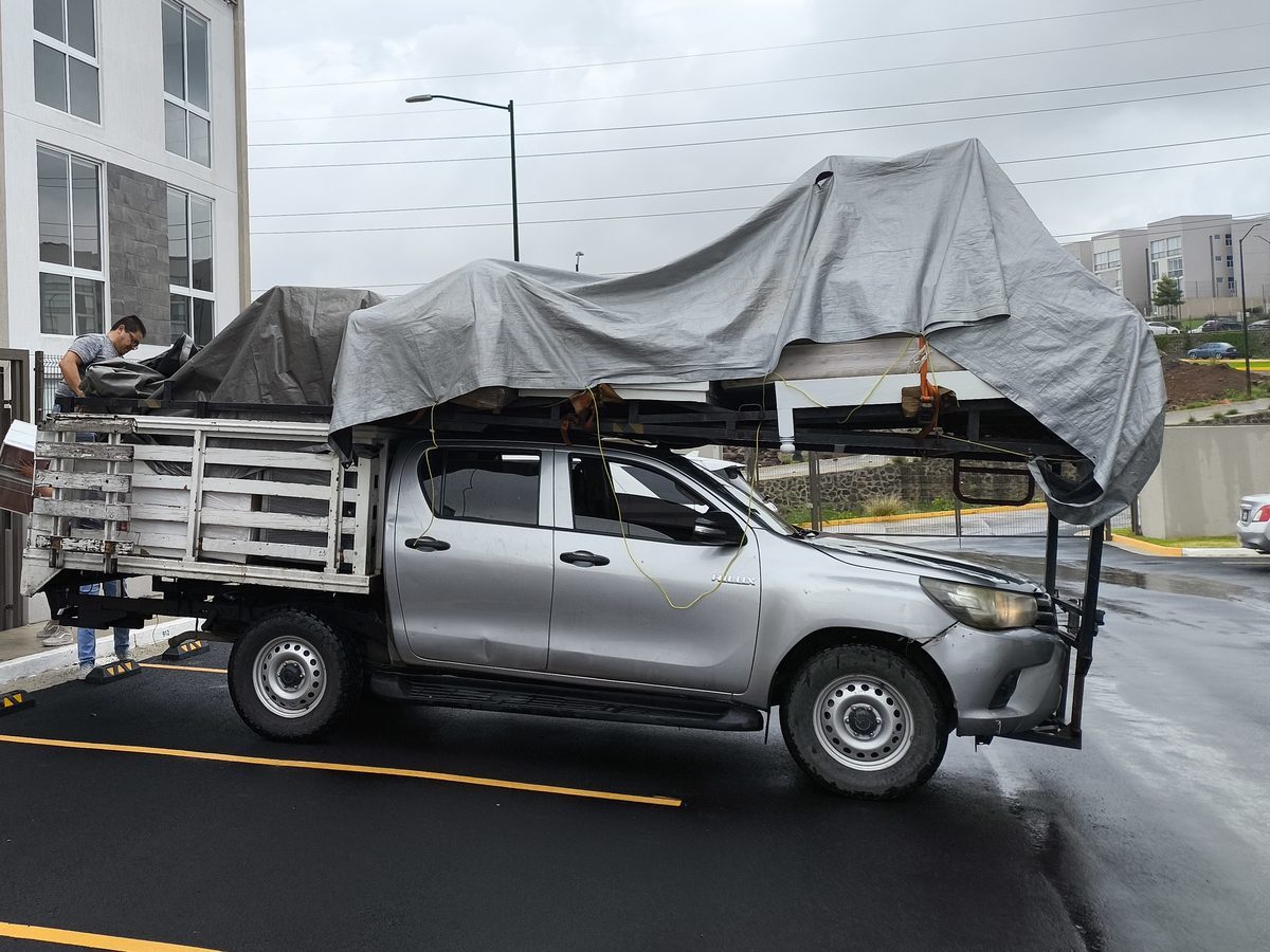 Hilux cargada con lona y un trabajador asegurando la carga